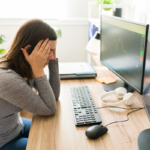 Mulher preocupada com RPV em frente a computadores com gráficos financeiros