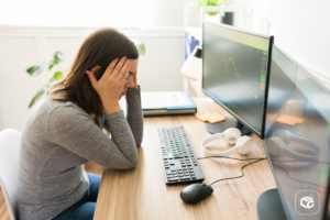 Mulher preocupada com RPV em frente a computadores com gráficos financeiros