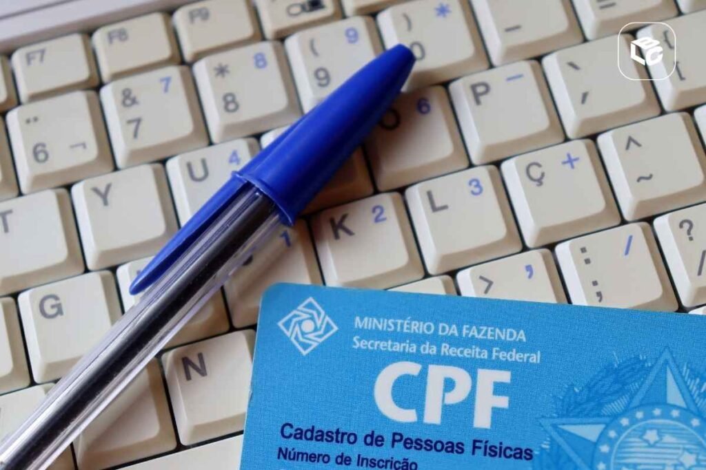 Caneta azul sobre teclado de computador com cartão CPF do Ministério da Fazenda